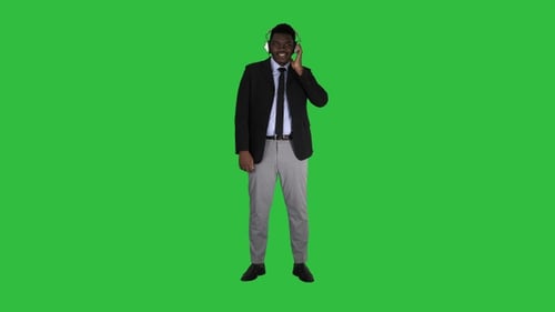 Young Man Listening on Headphones Against Green Screen