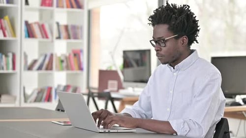 Young Adult Typing on Laptop in Office