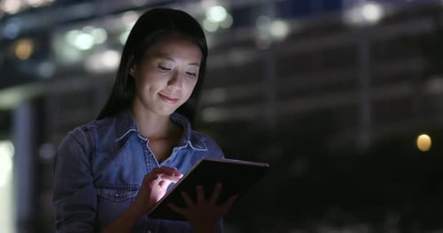 Woman use of tablet computer in city at night