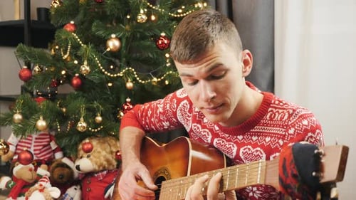 Man Plays Guitar By Decorated Christmas Tree