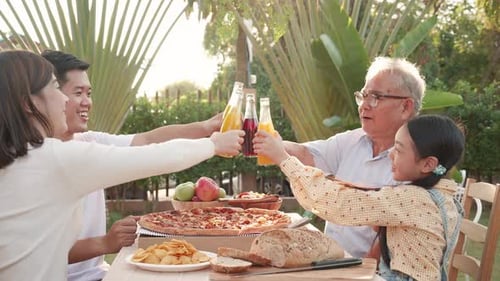 Family Celebrates With Pizza and Drinks Outdoors