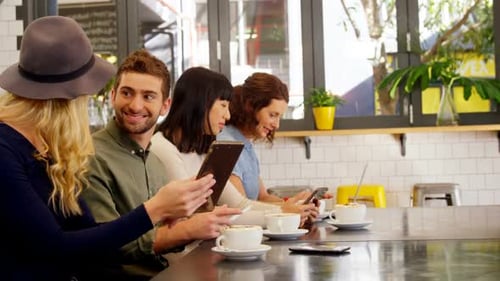 Friends Enjoying Coffee While Using Technology in Cafe