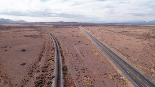 Drohnenaufnahme einer modernen Autobahn und alter Eisenbahnschienen, die weit weg führen