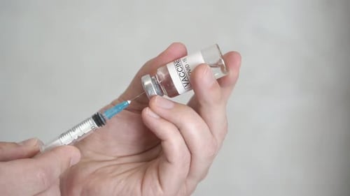 Der Arzt zieht den Coronavirus-Impfstoff in eine Spritze.
