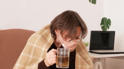 Man Drinks Tea and Blows Nose While Ill