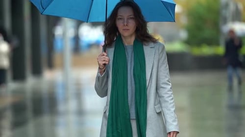 Adult Woman Is Strolling at Rainy Day in City, Holding Umbrella in Hand and Walking on Street