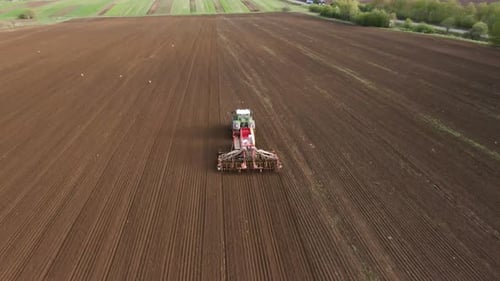 Tractor in Working in the Field. Tractor with a Modern Sowing Seeds Machine in a Newly Plowed Field