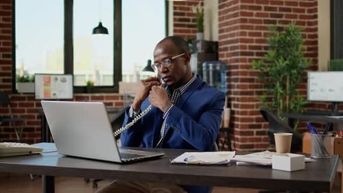 Man Working at Desk Answering Landline Phone