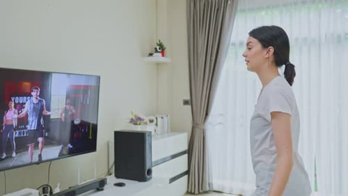 Hermosa joven asiática haciendo ejercicio aeróbico, siga las instrucciones del vídeo del entrenador.