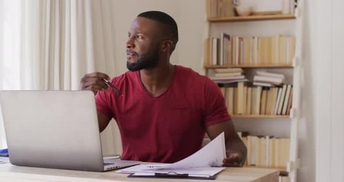 Man Working At Desk With Laptop and Paper