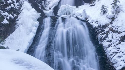 Frozen Waterfall Cascades Through Snowy Winter Wilderness