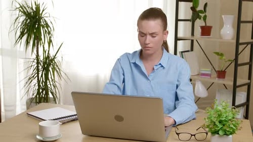 Woman Massaging Neck in Front of Laptop