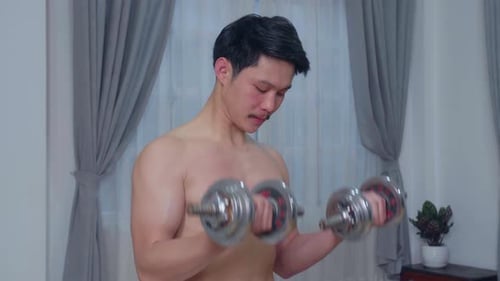 Man Does Bicep Curls with Dumbbells Indoors