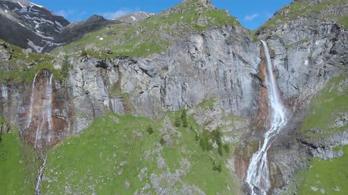 Aerial: drone flying over scenic waterfall and mountain stream on the italian Alps