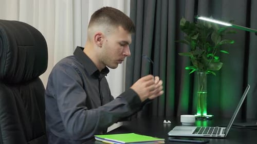 Businessman is sitting at workplace desk and preparing for work on laptop in office