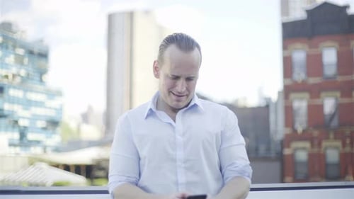 Man Uses Smartphone on Urban Rooftop