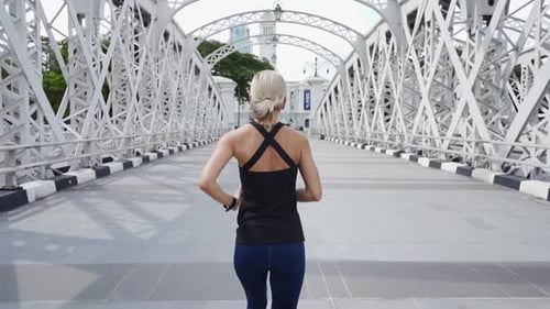 Young Asian Woman Runner Running on City Bridge Road with Cityscape on Background