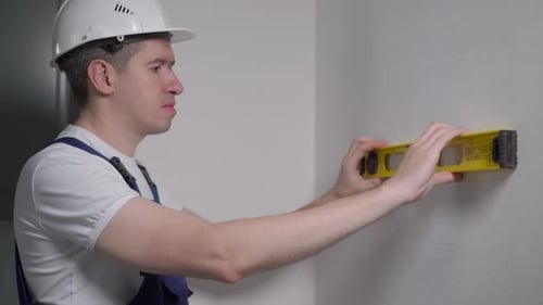Construction Worker Using a Level on a Wall