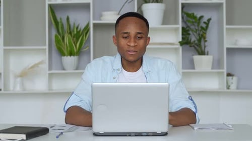 Young African-American Is Sitting at Home Office, Smiling at the Camera. Portrait of Satisfied Young