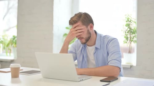 Stressed Man Working on Laptop at Desk