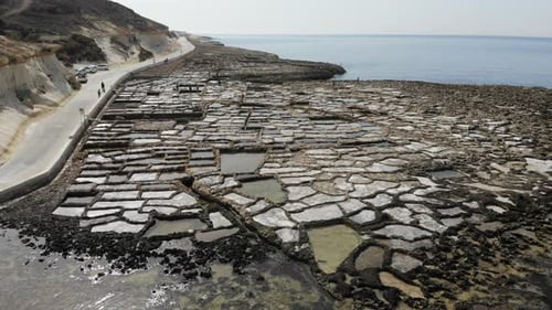 An aerial drone shot slowly ascending to reveal the scope of the ancient Gozo Salt Pans in Malta.