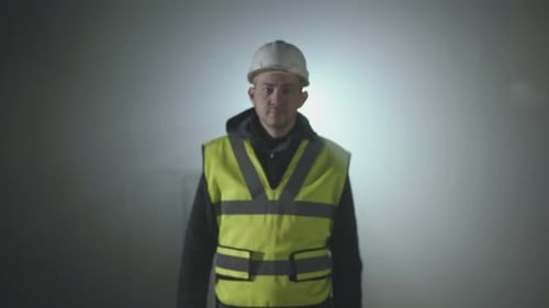 Man Wearing Hardhat and Vest Standing in Fog