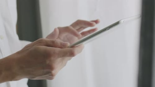 Close up hands businessman scrolling social media feed on a tablet.