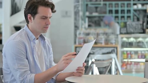 Creative Man Reading Documents in Cafe