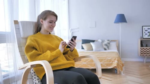 Woman Using Smartphone While Relaxing in Rocking Chair