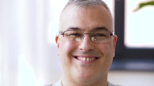 Man Smiles and Takes off Glasses Indoors
