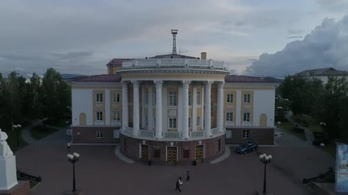 Aerial view of beautiful house of culture, square and alley. Summer, evening
