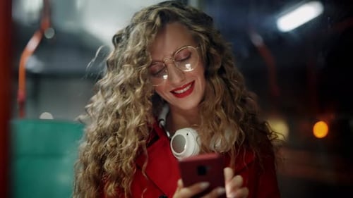 A Smiling Curly Woman is Using Smartphone and Reading Messages in Bus