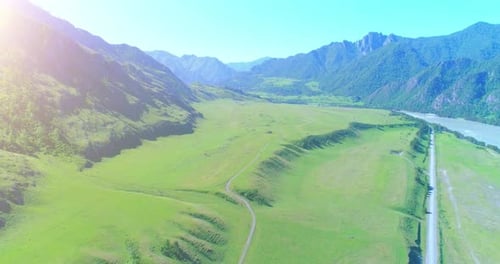 Aerial Rural Mountain Road and Meadow at Sunny Summer Morning. Asphalt Highway and River.
