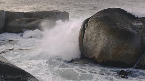 Big Waves Turn Into White Foamy Water After Hitting a Group of Giant Boulders
