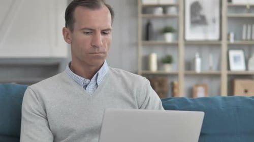 Man Using Laptop Computer While Sitting on Sofa