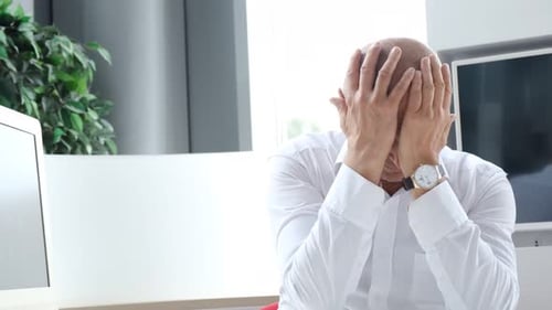 Stressed Man at Desk in Bright Office