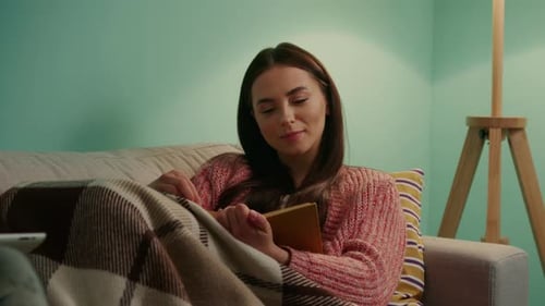Woman Reads a Book Comfortably on Couch