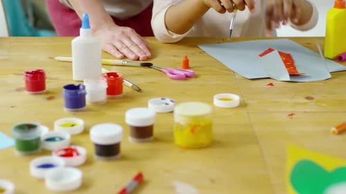 Nahaufnahme der Hände von Kindern beim Malen und Basteln von Papier im Kunstunterricht