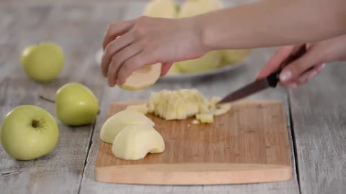 Young Woman's Hands Cutting an Apple on Wooden Cut Board