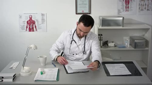 Young Serious Doctor Sitting in Medical Office with Folder and Reading Documents