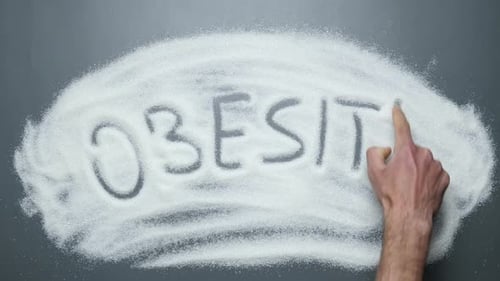 Hand Writes 'Obesity' in White Granulated Sugar