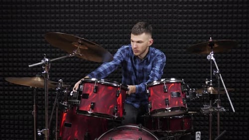 Drummer is tuning drum kit in professional rehearsal studio
