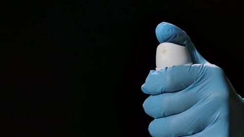 Gloved Hand Sprays Liquid from Can