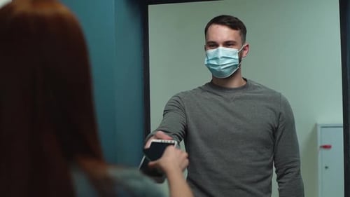 Zusteller mit schützender Gesichtsmaske gibt POS Wireless Terminal für kontaktloses Bezahlen
