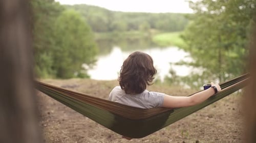 Woman Relaxing in Hammock Overlooking Scenic Lake