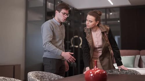 Male Expert Talking Explaining Furniture Set Quality As Wealthy Woman Touching Furnishings in