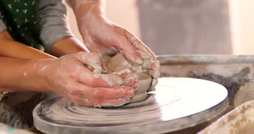 Adult and Child Shaping Clay on Pottery Wheel