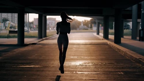A Young Woman Runner is Training in the Summer Within a City