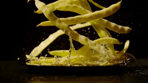 Stringbohnen fallen mit Wasser auf einen Teller, Ultra Zeitlupe