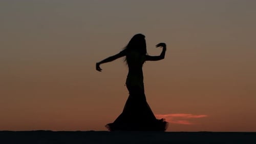 Girl Is Dancing Belly Dancing Against the Beautiful Sunset on the Beach. Silhouettes